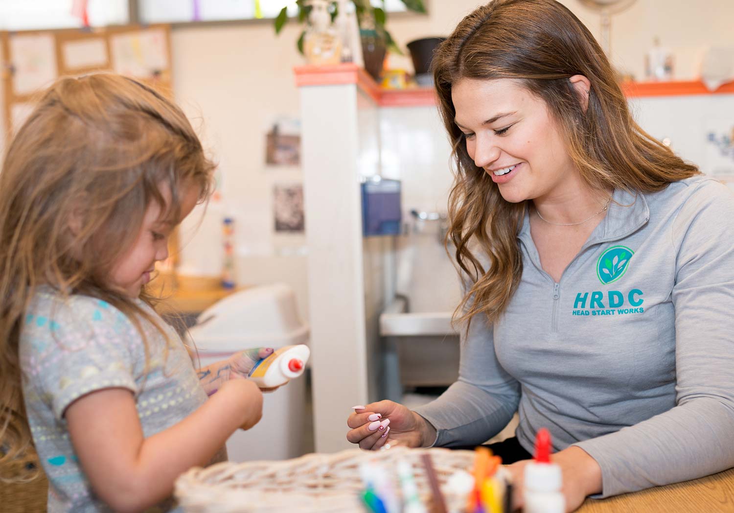 Photo of an Early Childhood Education employee doing a craft project with a little girl.