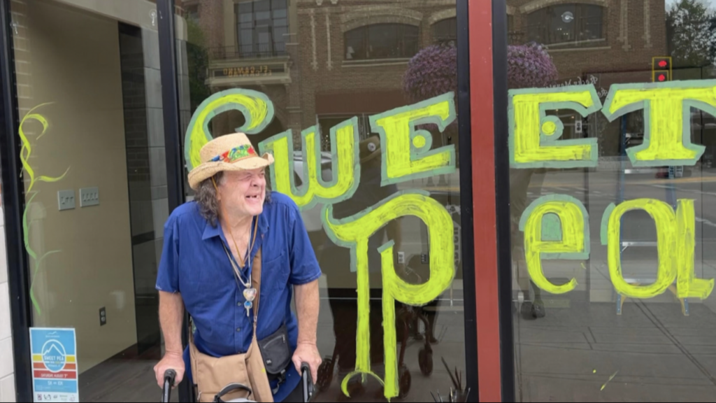 Photo of Buzzard in front of a window with window art he painted.