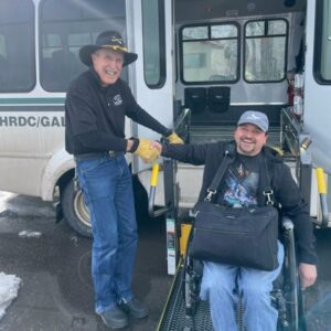 Photo of the Galavan driver shaking hands with a rider who uses a wheelchair. 